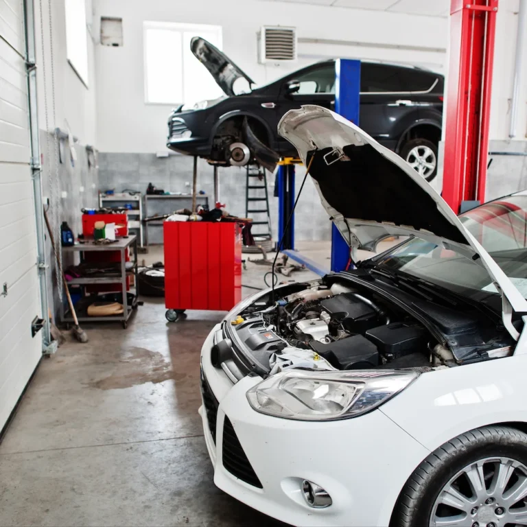 Gebrauchtwagen Ford Focus steht mit offener Motorhaube in einer Autowerkstatt und wird auf Mängel geprüft